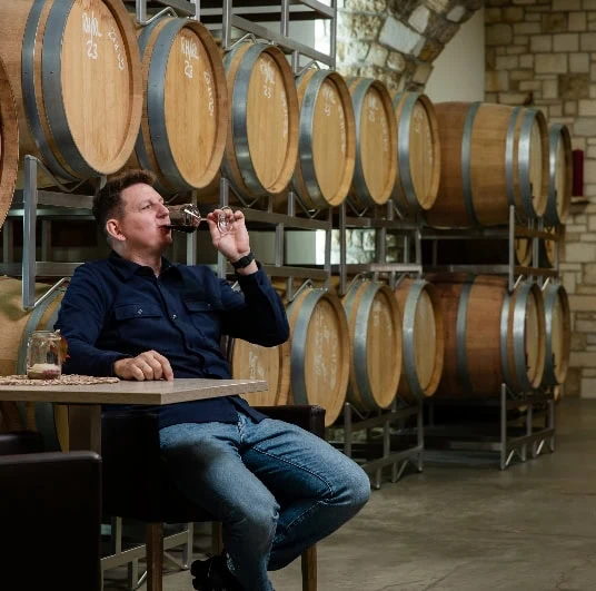 Markus Königshofer trinkt ein Glas Rotwein im Barriqueraum.