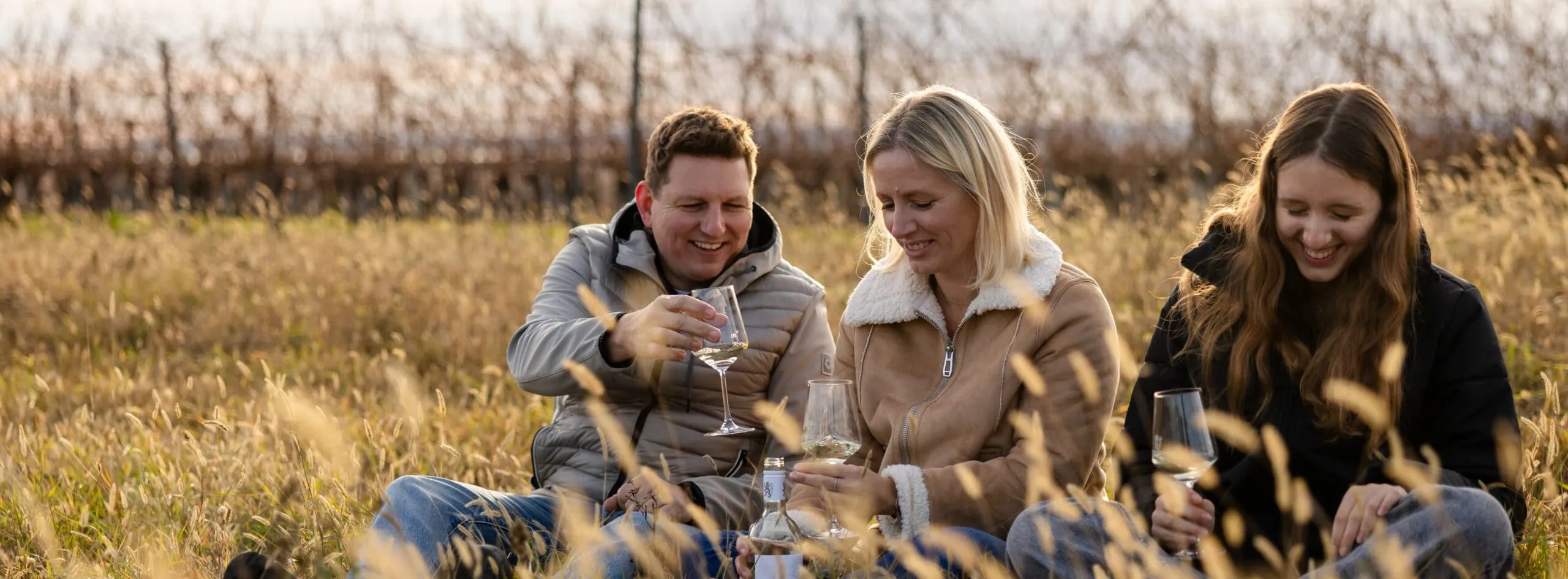 Weingut Koenigshofer Familie Königshofer sitzt am Feld mit Glas Wein