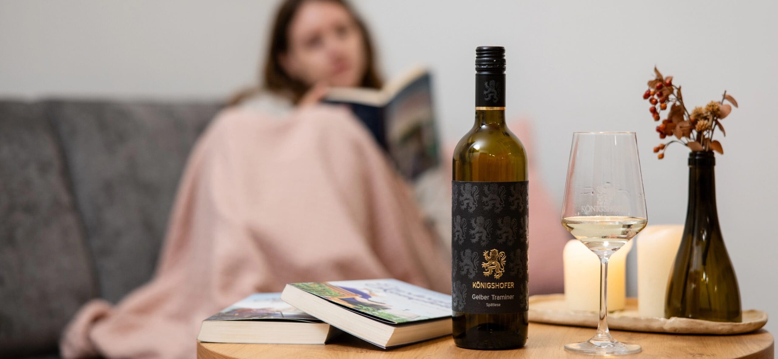 Weingut Koenigshofer Frauz auf Sofa liest Buch Flasche Wein