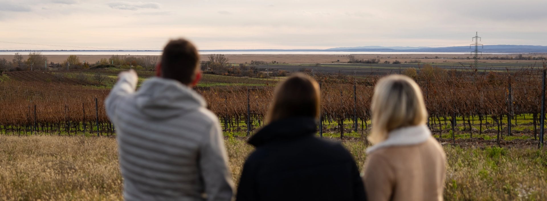 Familie Königshofer steht am Weinberg und schaut in Richtung See